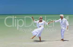 Happy Senior Couple Dancing Holding Hands on A Tropical Beach