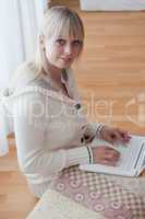 young blond woman sits with a laptop on the floor