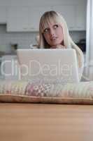 young blond woman lies with a laptop on the floor