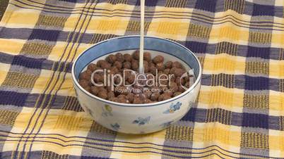 Pouring milk in chocolate cereal flakes in bowl