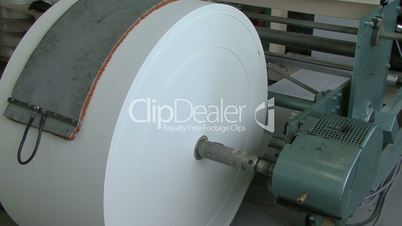 huge roll of white paper rotating in factory