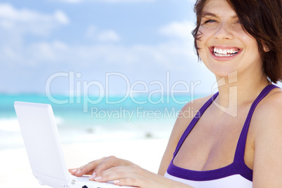 woman with laptop computer on the beach