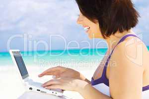 woman with laptop computer on the beach
