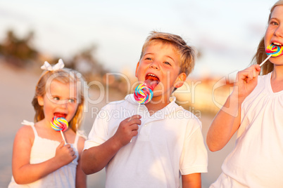 Cute Brother and Sisters Enjoying Their Lollipops Outside