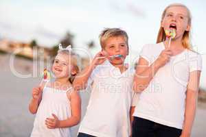 Cute Brother and Sisters Enjoying Their Lollipops Outside