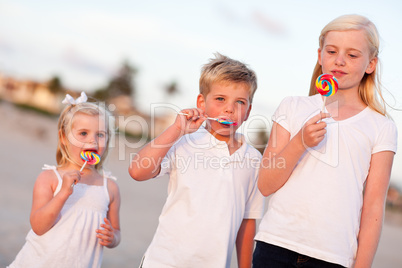 Cute Brother and Sisters Enjoying Their Lollipops Outside