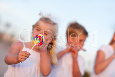 Cute Brother and Sisters Enjoying Their Lollipops Outside