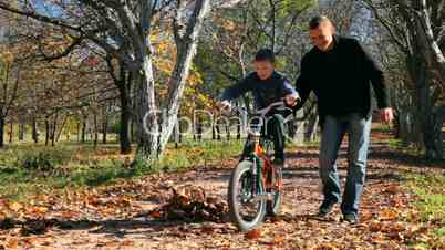 father teaches his son to ride a bicycle