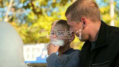 father and son eating cotton candy