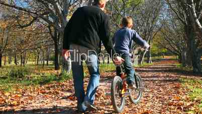father teaches his son to ride a bicycle