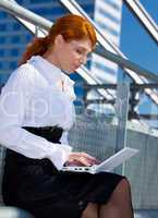 happy businesswoman with laptop in the city