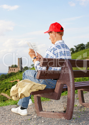 Senior reading Book outdoors - Panorama View