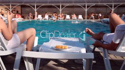 ouple enjoying relaxing vacation poolside eating chips
