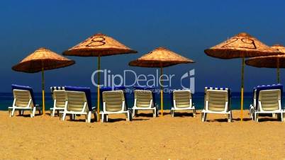 Sun loungers on an empty beach with clear blue sky