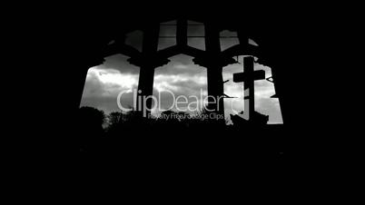 Looking at graveyard through derelict arched church windows