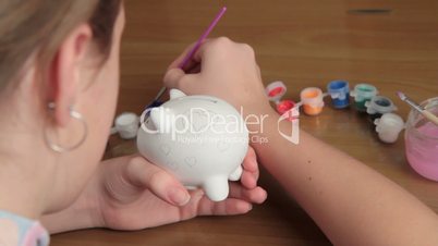 girl paints pig-coin box.