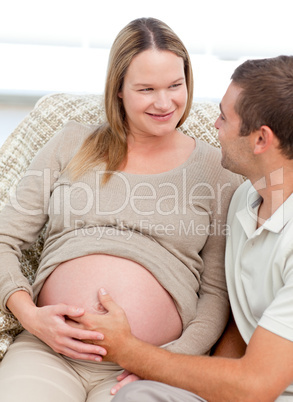 Lovely pregnant woman touching her belly with her husband