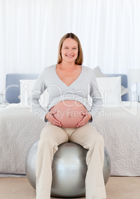 Pretty future mother sitting on a fitness ball and touching her