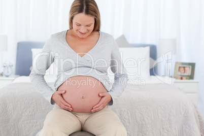 Adorable future mom touching her belly sitting on a fitness ball