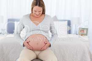 Adorable future mom touching her belly sitting on a fitness ball