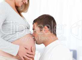 Lovely future dad kissing the belly of his wife