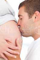 Future father kissing the belly of his pregnant wife