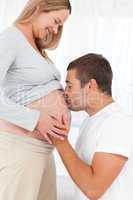 Adorable future dad kissing the belly of his wife