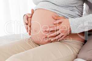 Side view of a pregnant woman touching her belly with her husban