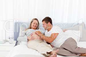 Cute man playing with his pregnant wife