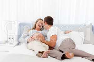 Smiling future parents liyng on the bed