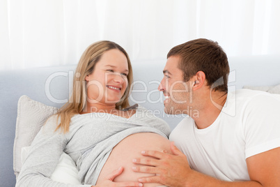 Lovely future parents resting on a bed