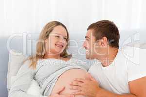 Lovely future parents resting on a bed