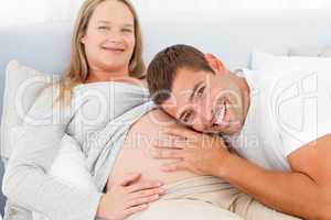 Portrait of a man listening the belly of his pregnant wife