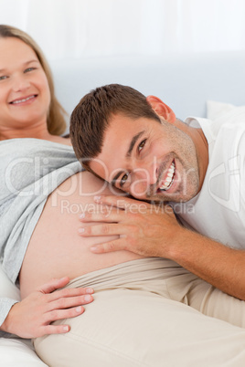 Cheerful man listening the belly of his pregnant wife