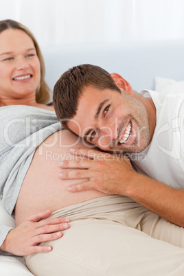 Happy man listening the belly of his pregnant wife