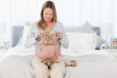 Pretty future mom knitting sitting in her bedroom
