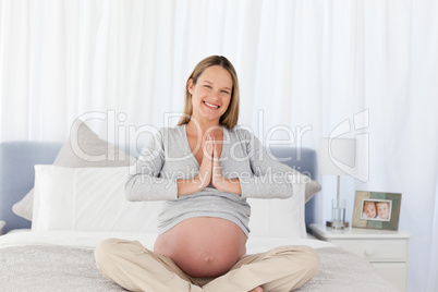 Adorable future mom doing meditation sitting on the bed