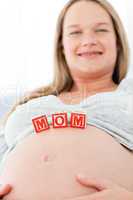 Close up of a woman having mom letters on her belly lying on a b