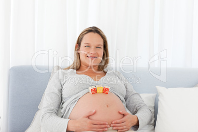 Portrait of a pregnant woman having mom letters on her belly