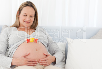 Pretty pregnant woman with letters on her belly