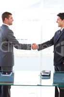 Cheerful businessmen closing a deal by shaking their hands