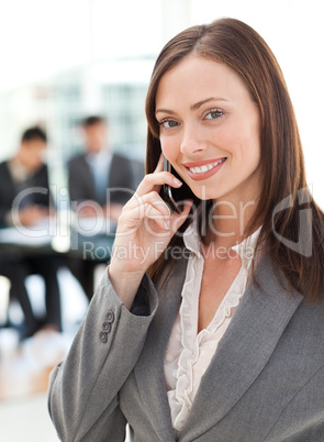 Happy businesswoman on the phone while her team is working