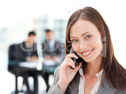 Captivating businesswoman on the phone while her team is working
