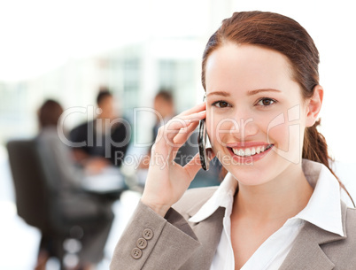 Attractive businesswoman on the phone while her team is working