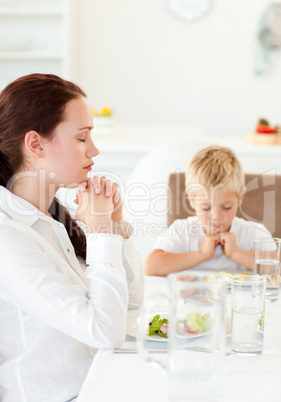 concentrated mother and son praying during the lunch