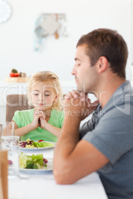 Concentrated father and daughter praying before eating their sal