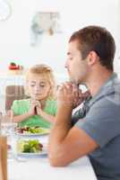 Concentrated father and daughter praying before eating their sal