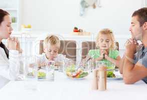 Portrait of a family praying together during the lunch