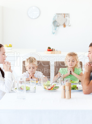 Parents and their children praying during their lunch