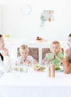 Parents and their children praying during their lunch